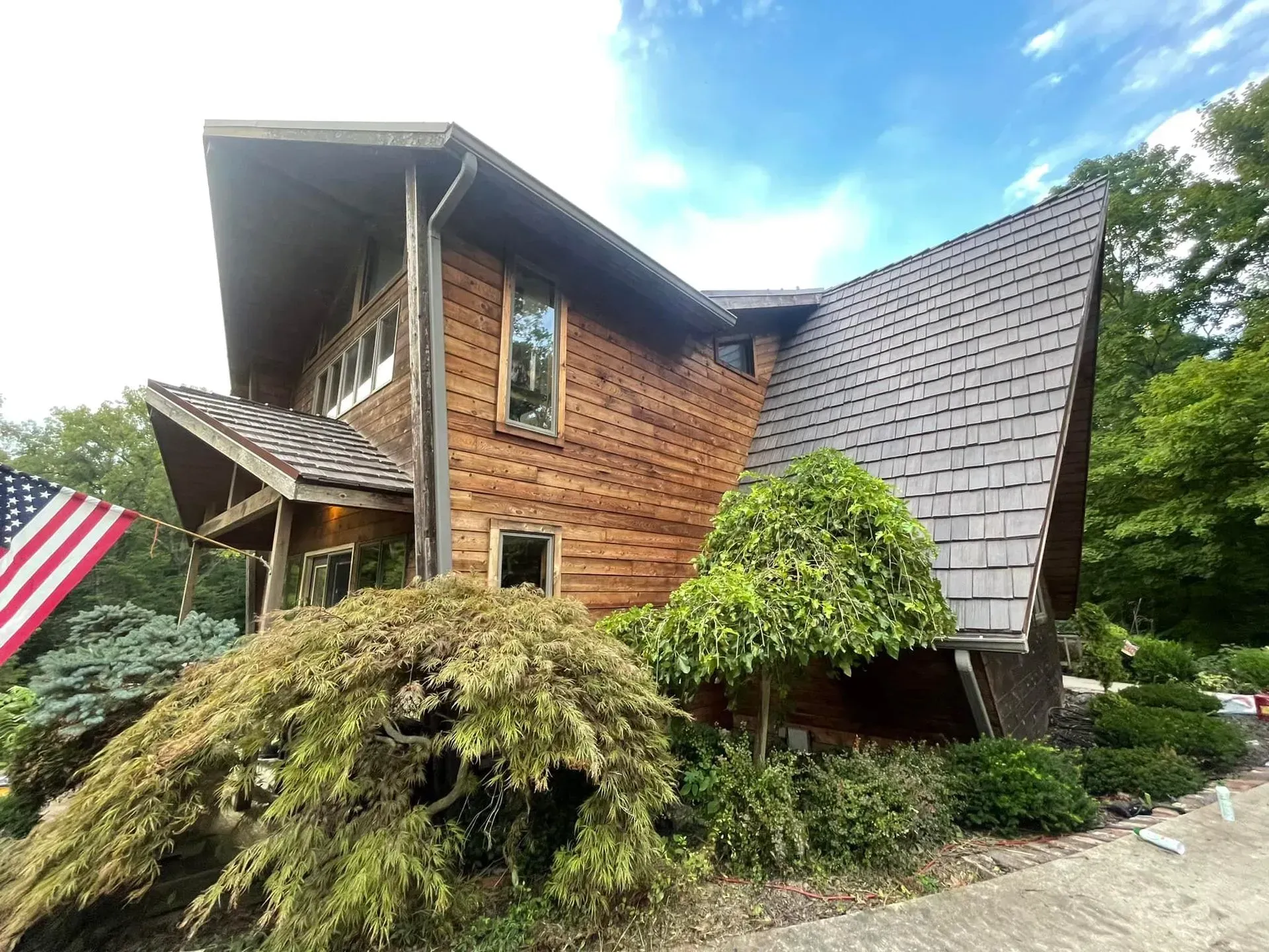 A large wooden house with a roof and a tree in front of it.