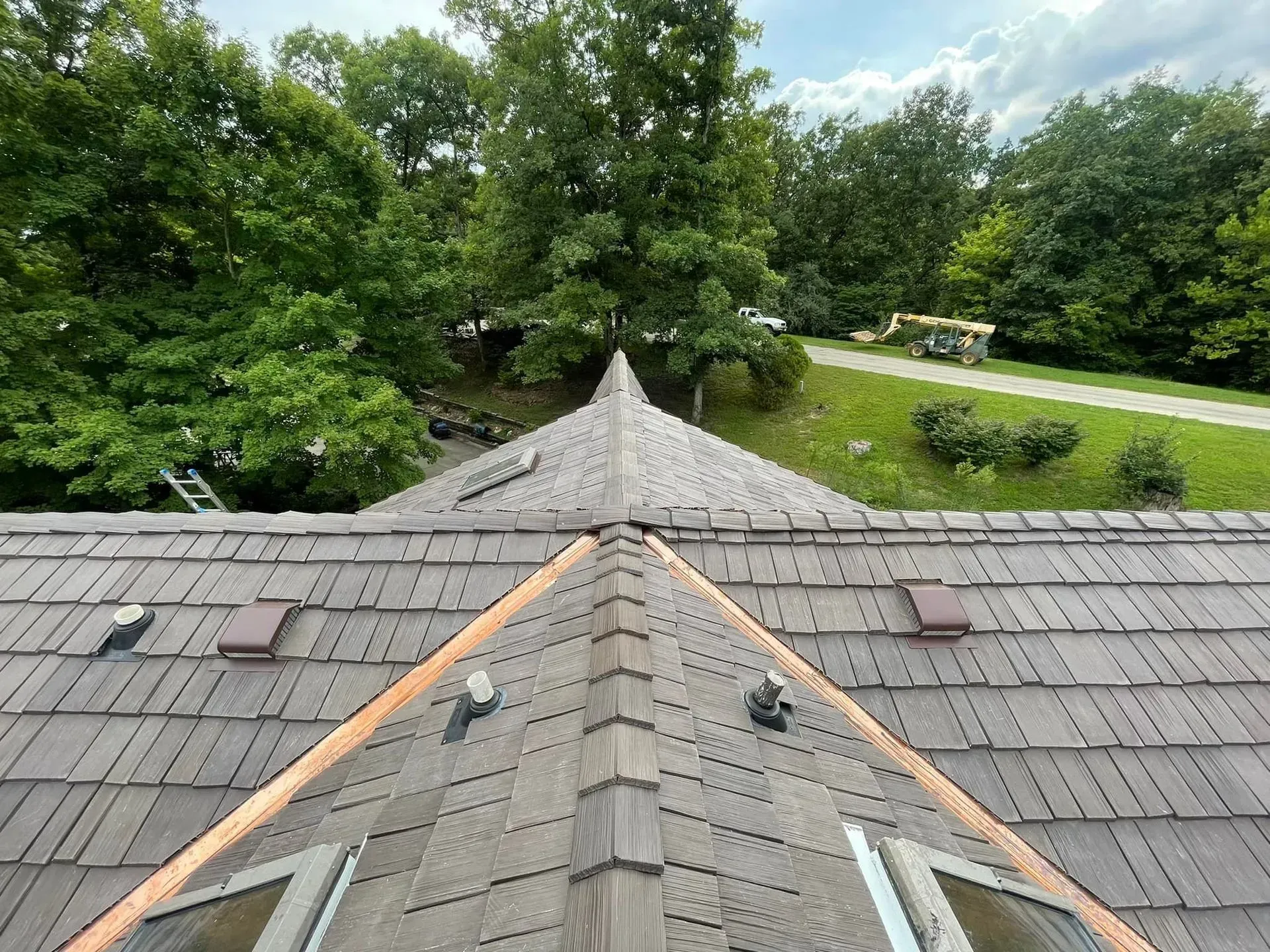 An aerial view of a roof with a triangle shaped roof and trees in the background.