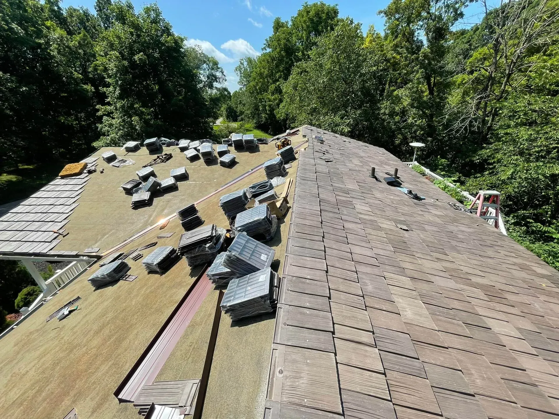 A roof with a lot of shingles on it and trees in the background.