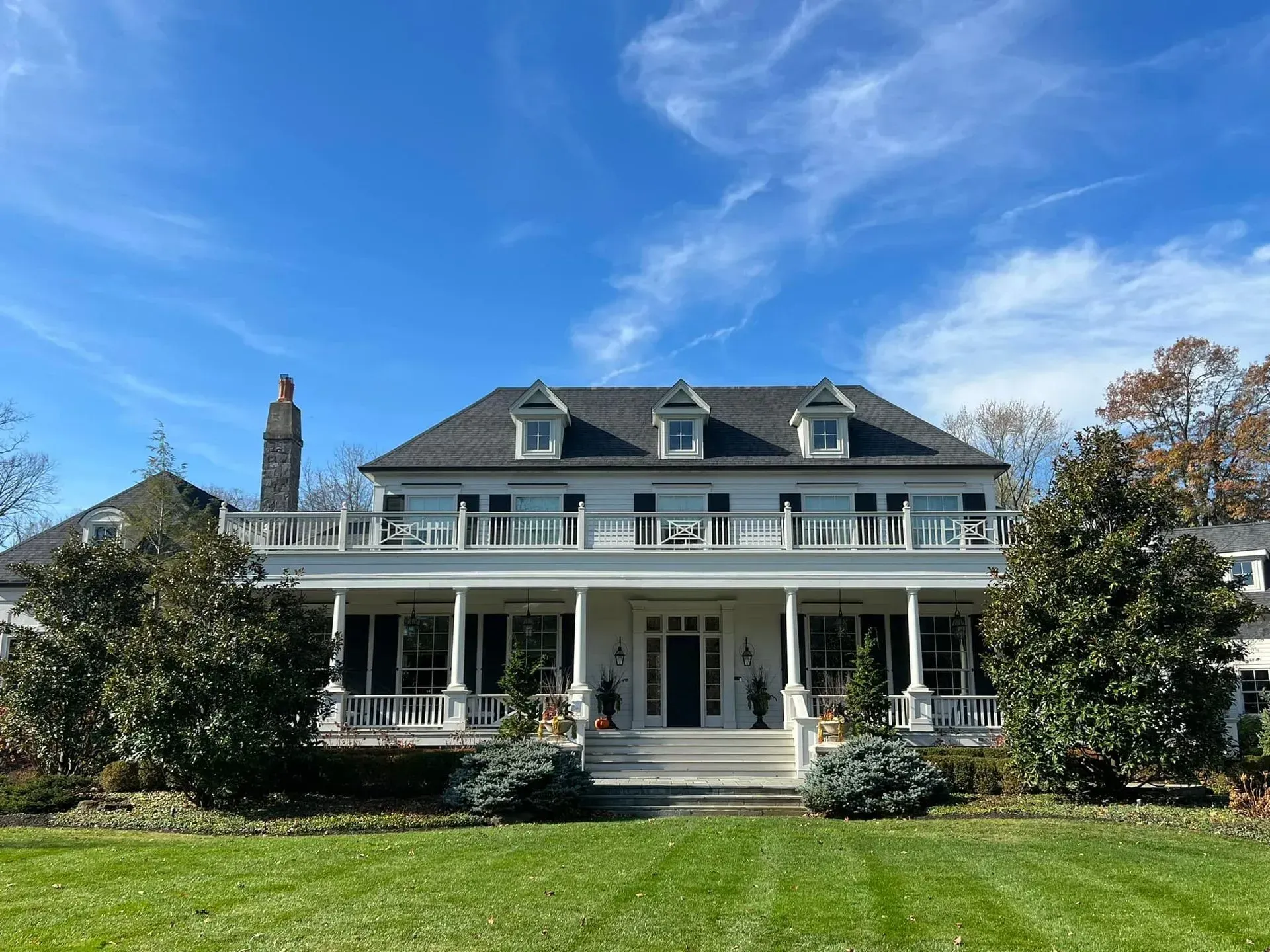 A large white house with a large porch on a sunny day.