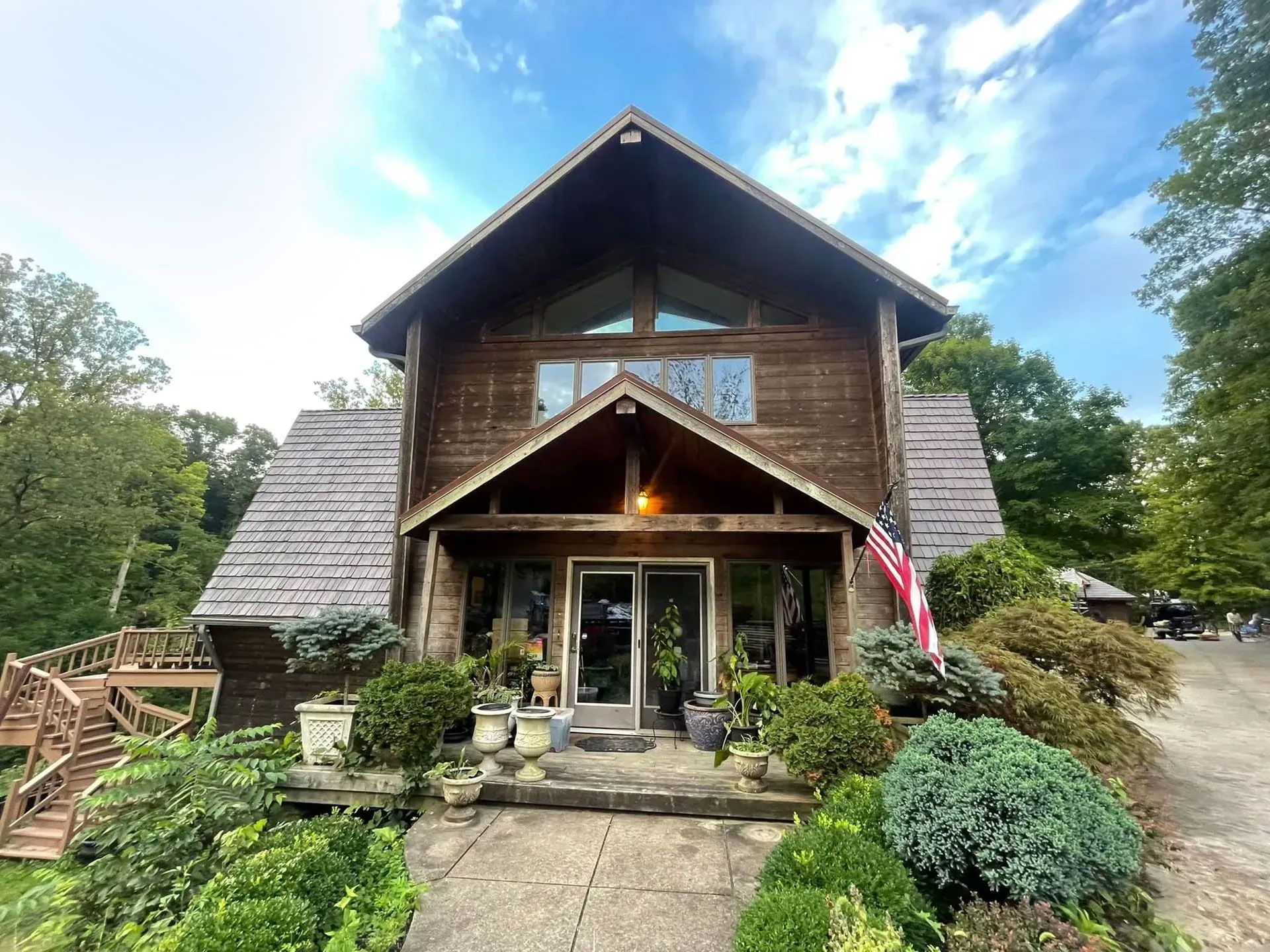 A large wooden house with a roof that is surrounded by trees and bushes.