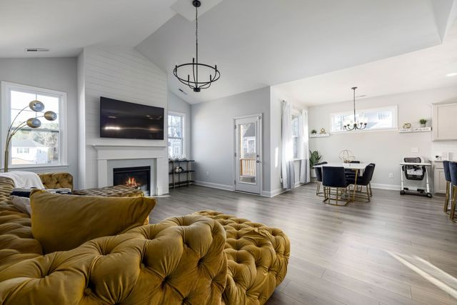 Bright modern living room with mustard sofa, fireplace, TV, and open dining area