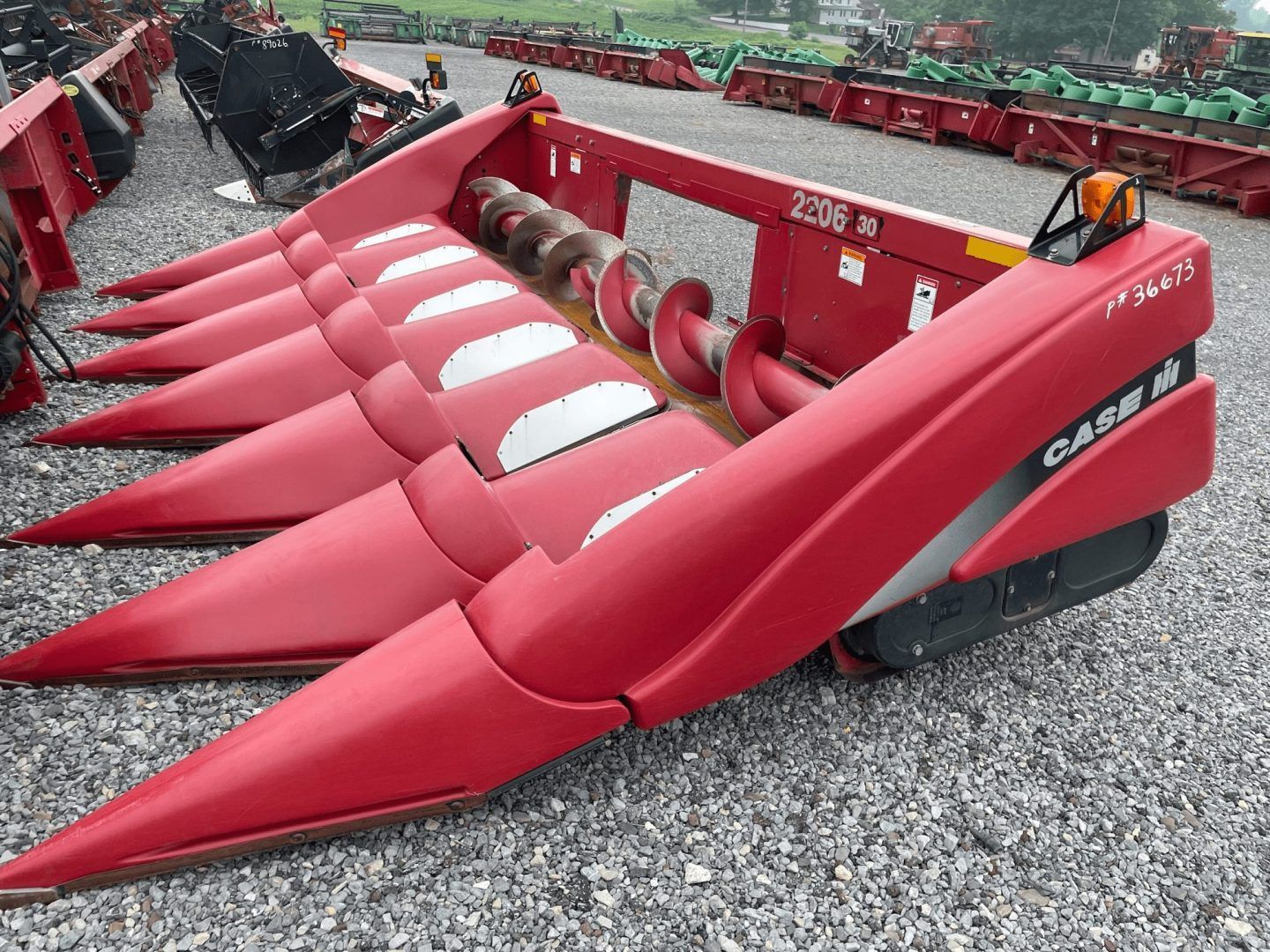 Red corn header with pointed red snouts on a combine parked on gravel