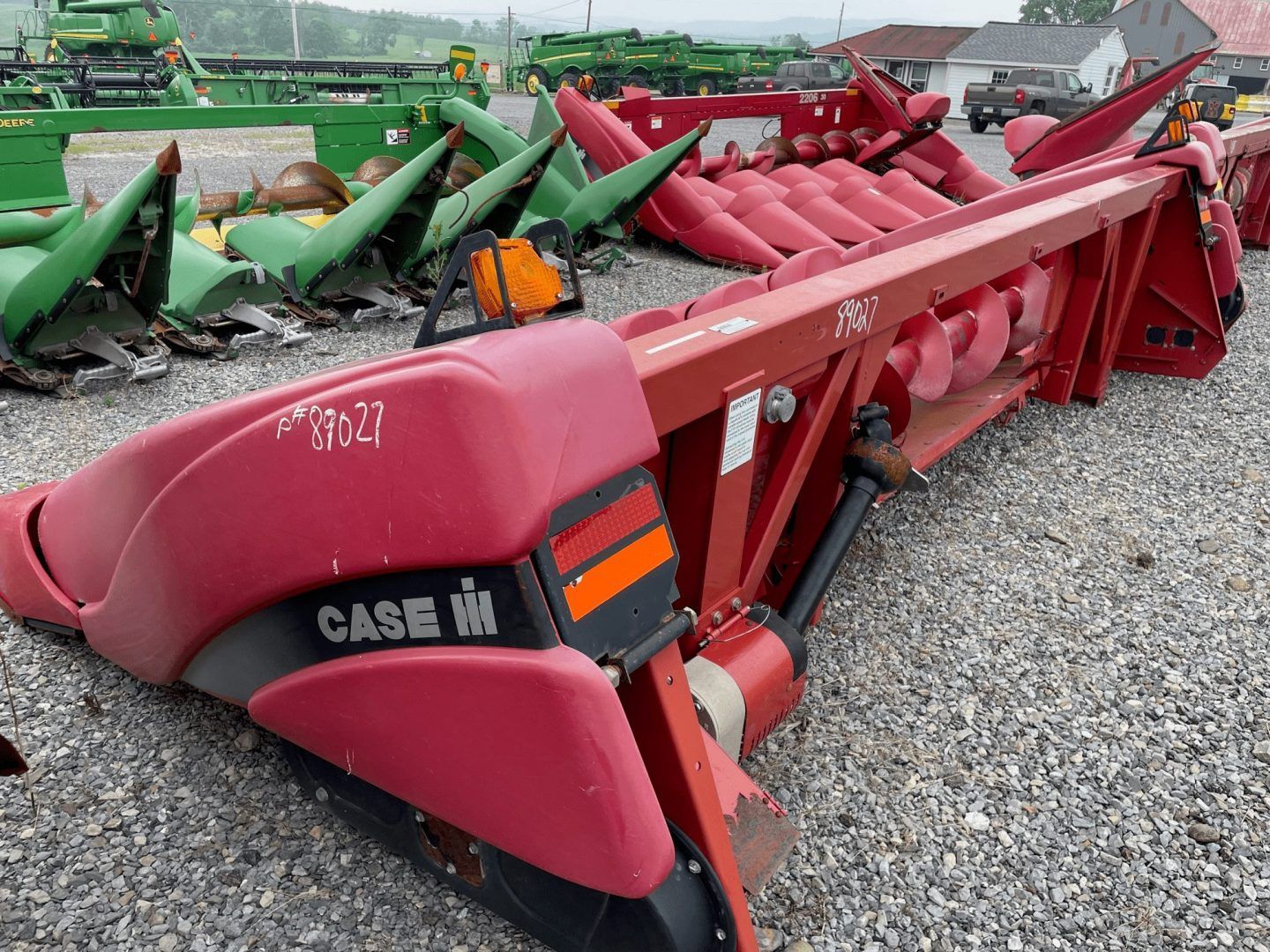 Red Case IH combine header on gravel lot among other farm equipment