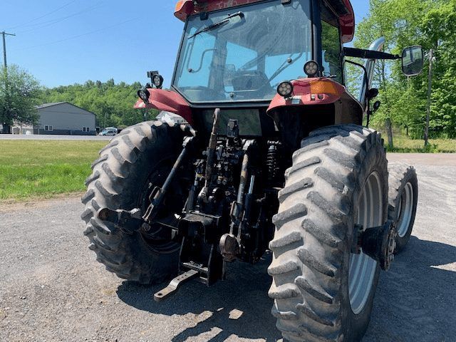 Red tractor with large rear tires parked on a sunny rural road