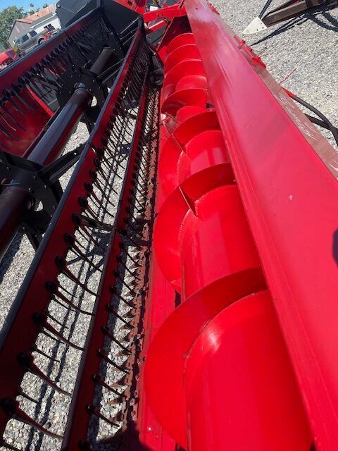 Red industrial machine with black conveyor tracks and bright red metal panels outdoors