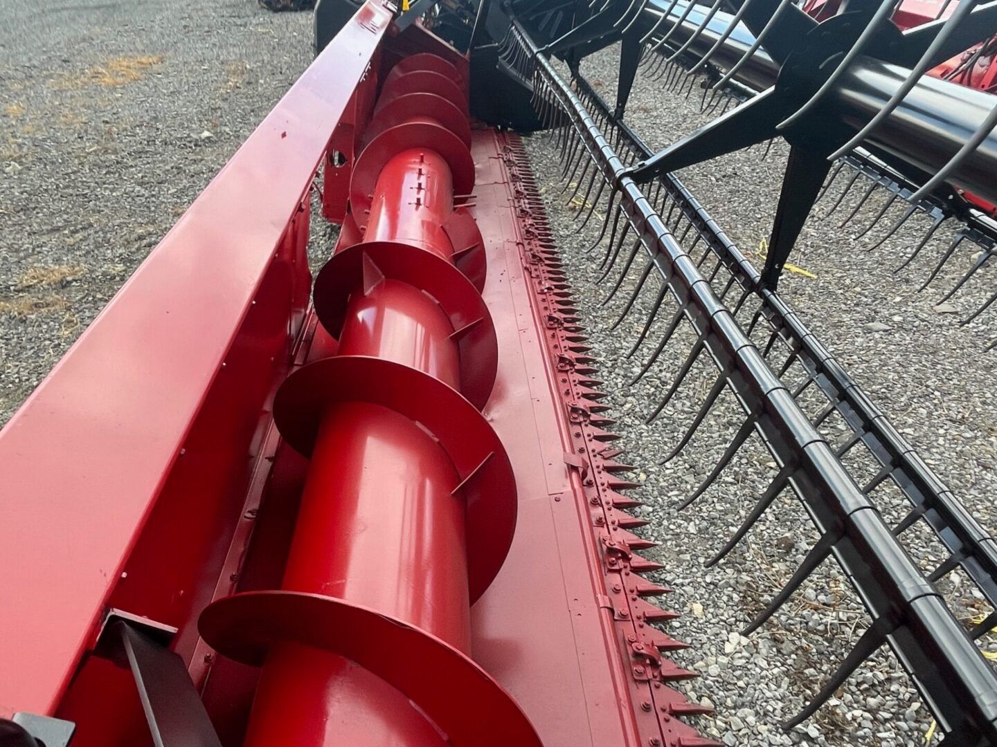 Red auger conveyor beside a gravel pit, viewed from above.