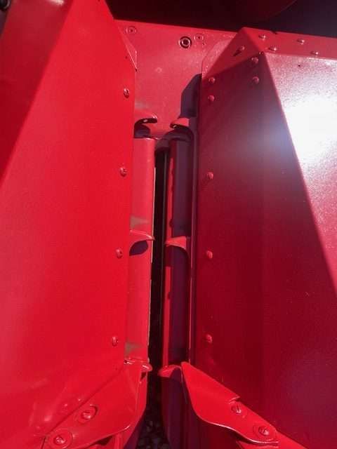 Close-up of a red metal machine interior with bolts and narrow black parts.