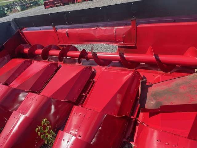 Close-up of bright red metal roof tiles with a row of black pipes along the top edge