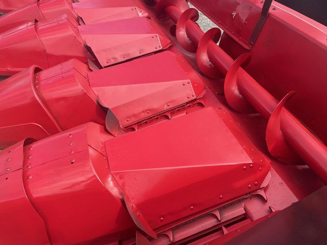 Red industrial machinery with bright red metal hoppers and conveyor augers in close-up