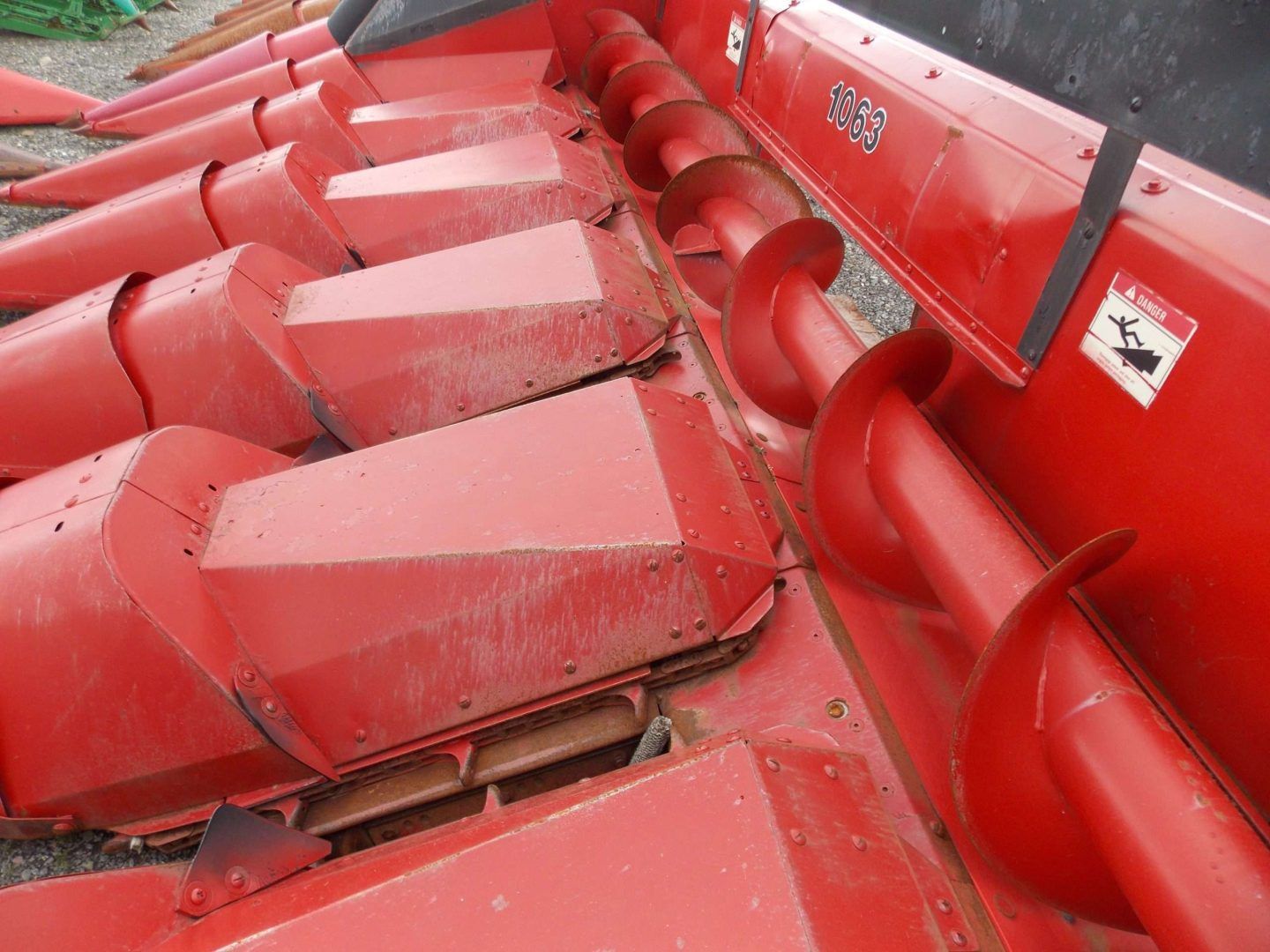 Close-up of red agricultural machinery with metal paddles and rollers, coated in dust and wear