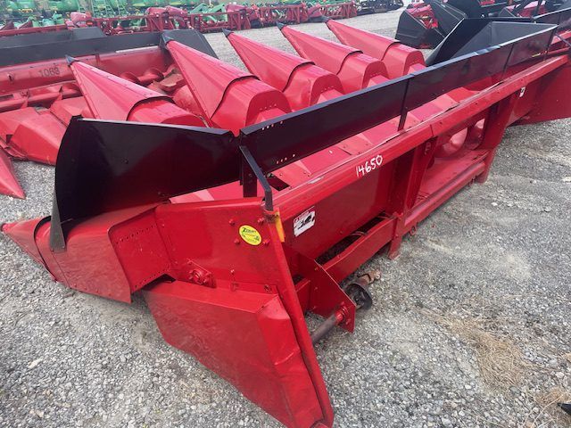 Red agricultural combine header attachment with red augers on a gravel lot