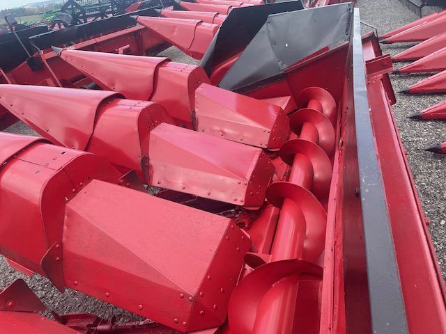 Red industrial machine parts stacked in a yard