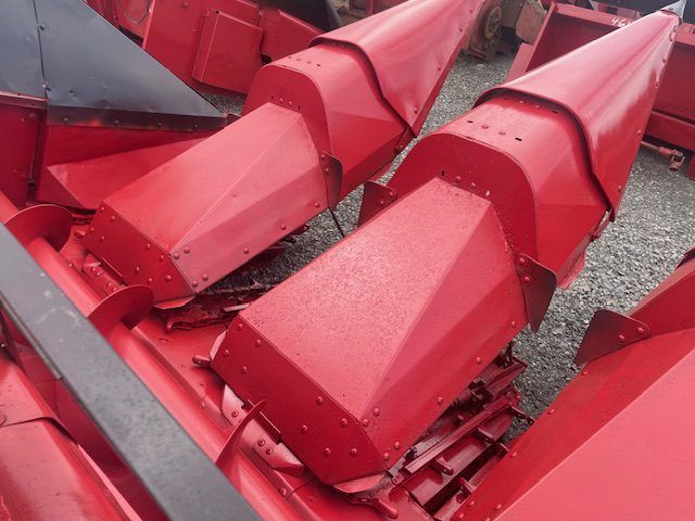 Red combine harvester corn headers stacked together, painted bright red.