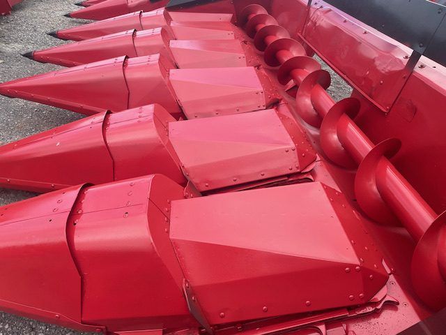 Red industrial metal auger blades and components stacked together on a surface