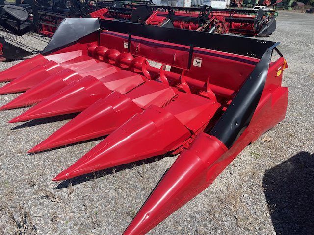 Red farm corn header with red pointed snouts and black sides on gravel