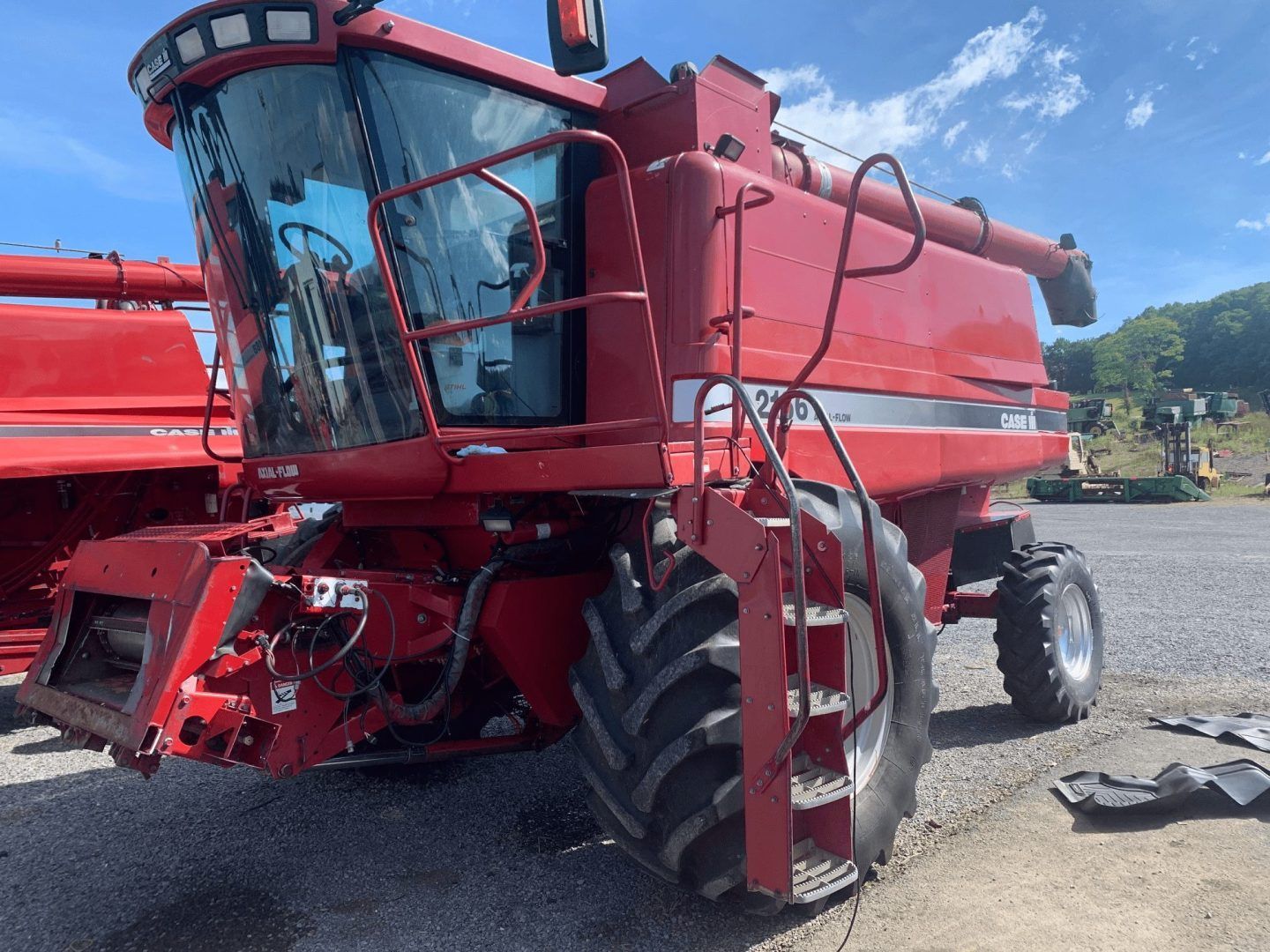 Red combine harvester in a gravel lot under a blue sky