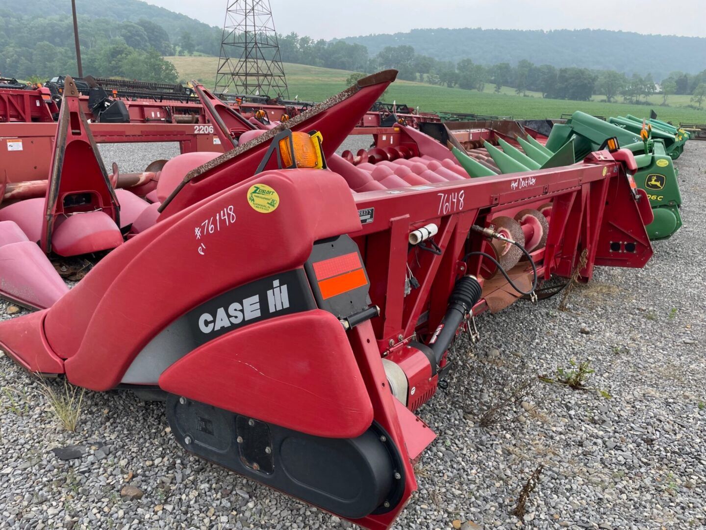 Red Case IH farm implement with multiple red arms parked on gravel outdoors.