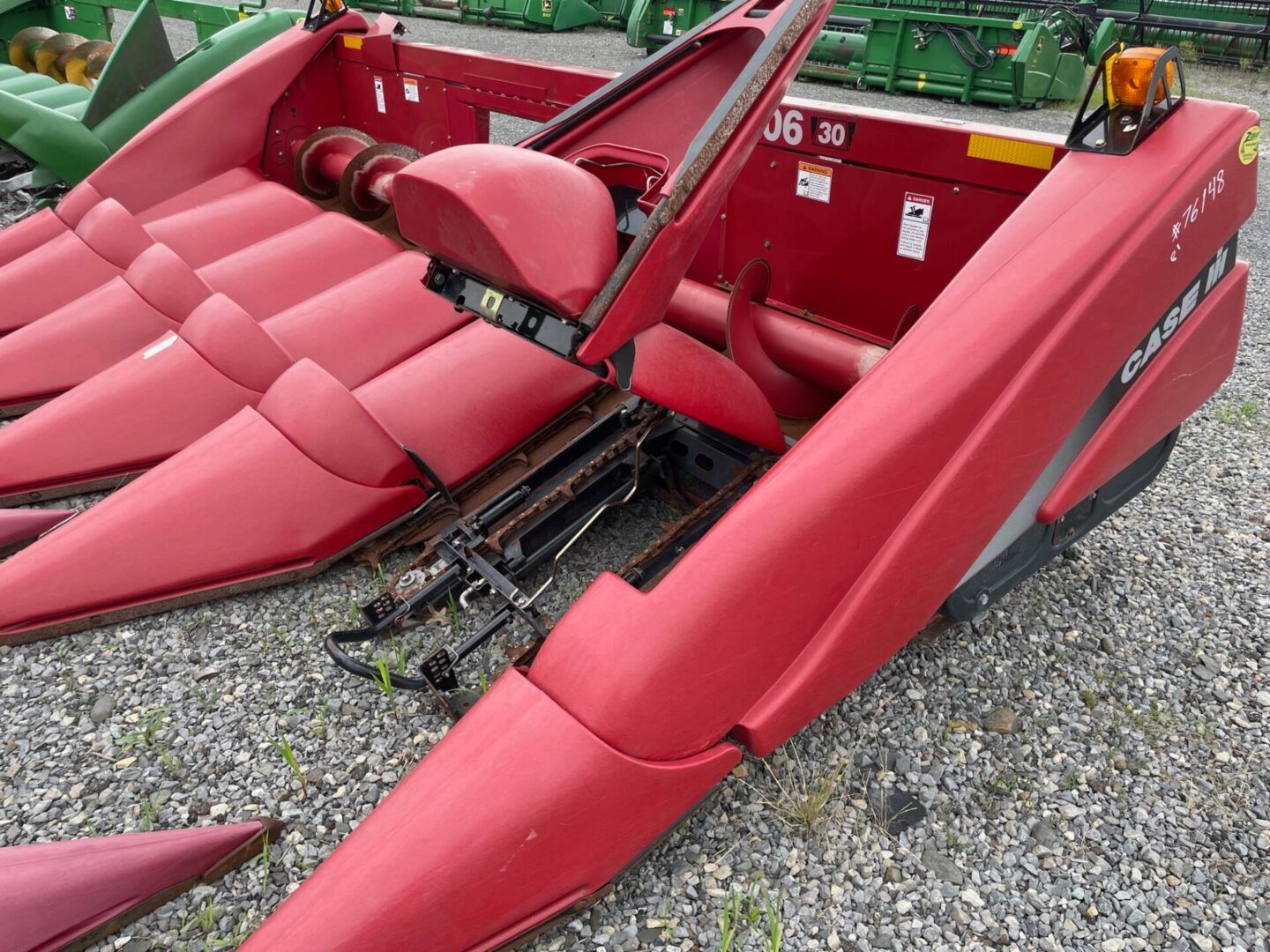 Red agricultural machine with red seats and open panels on gravel lot
