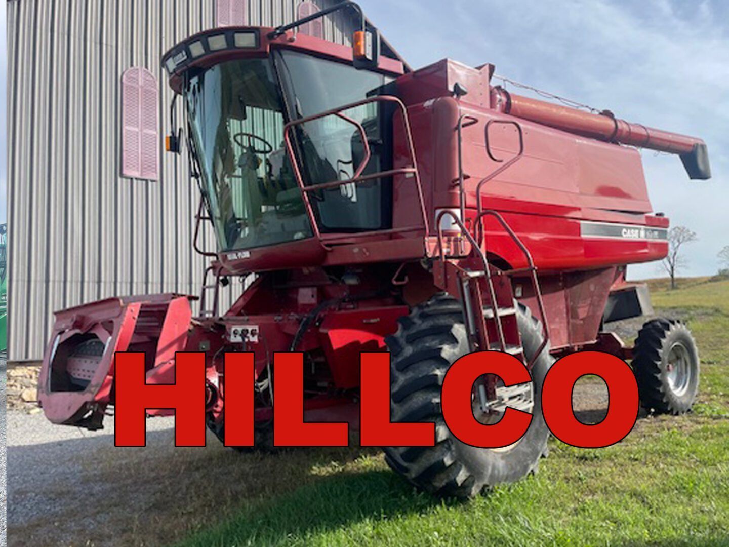 Red combine harvester in a grassy field with large red “HILLCO” text in front