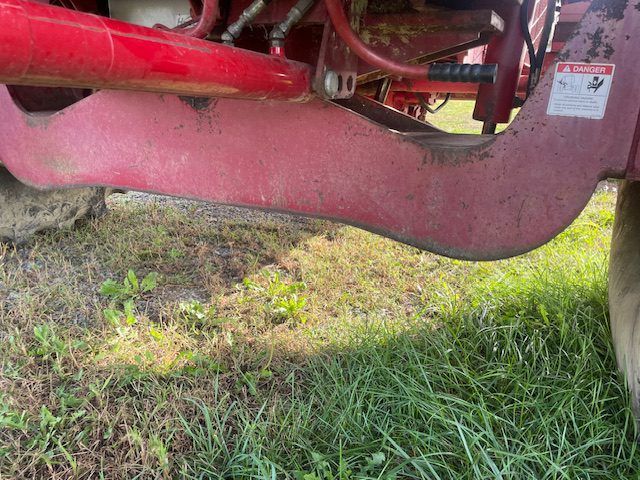 Close-up of a red farm machine hitch and wheel over grass in a field