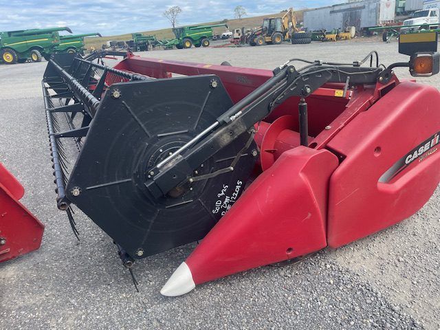 Red Case IH combine header on gravel, with black reel and white pointed end caps