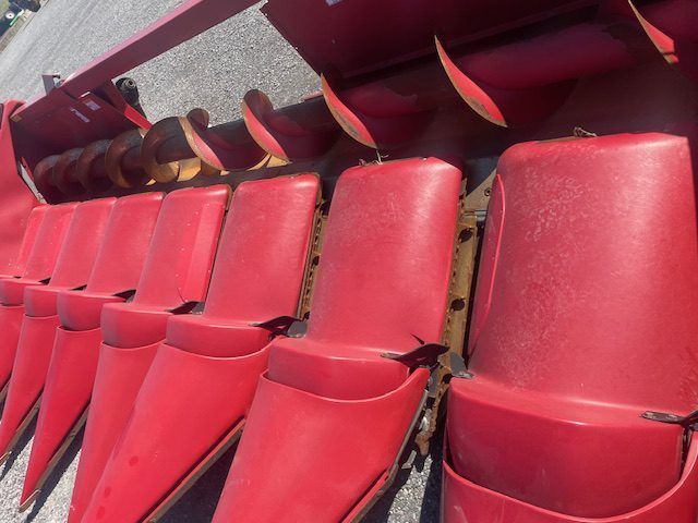 Rows of red stadium seats with folded armrests in a maroon seating section