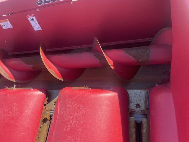 Close-up of a red machine with three curved metal blades above red seats or cushions