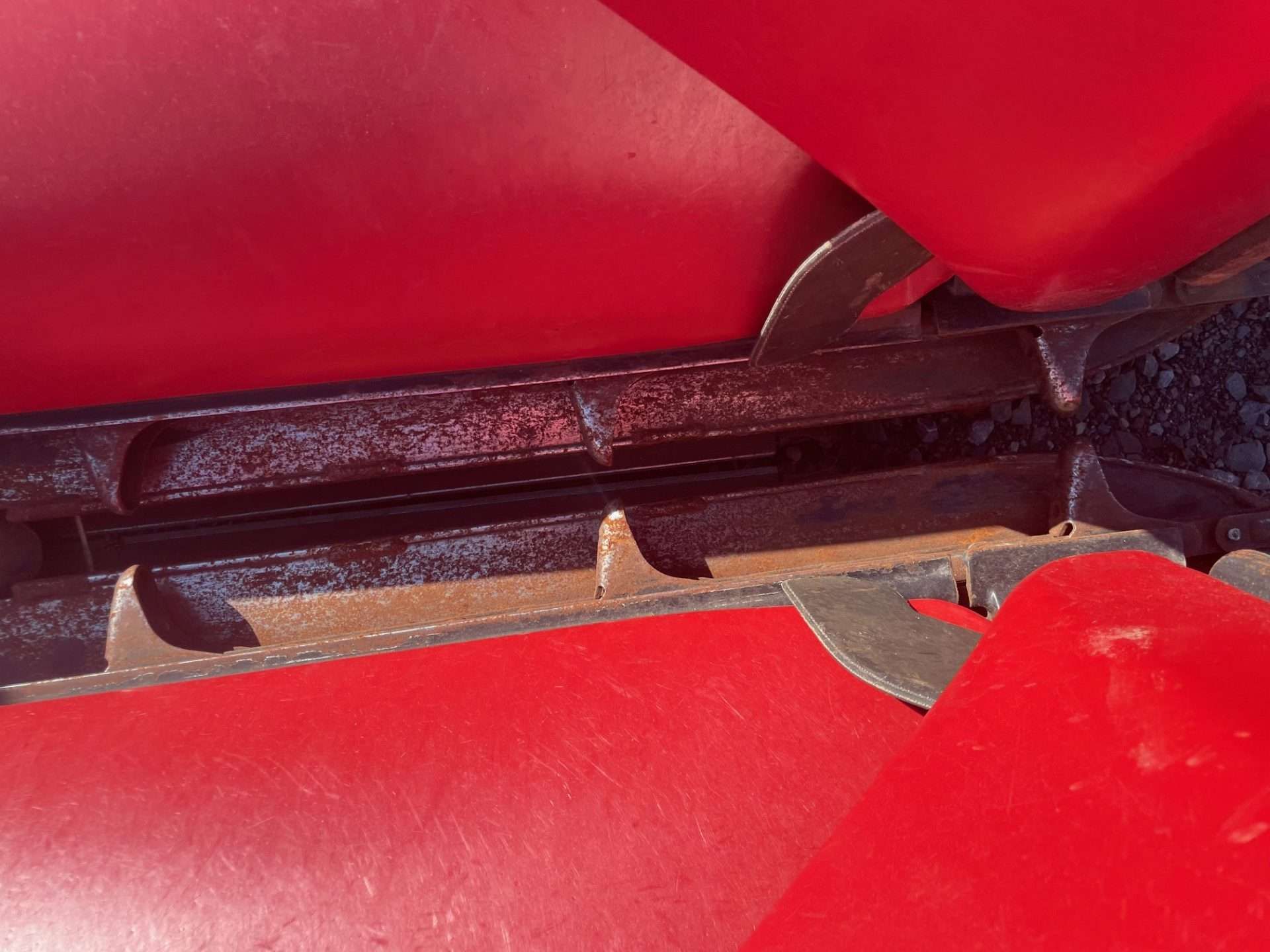 Close-up of red plastic seats with a black metal hinge and worn tan residue between them