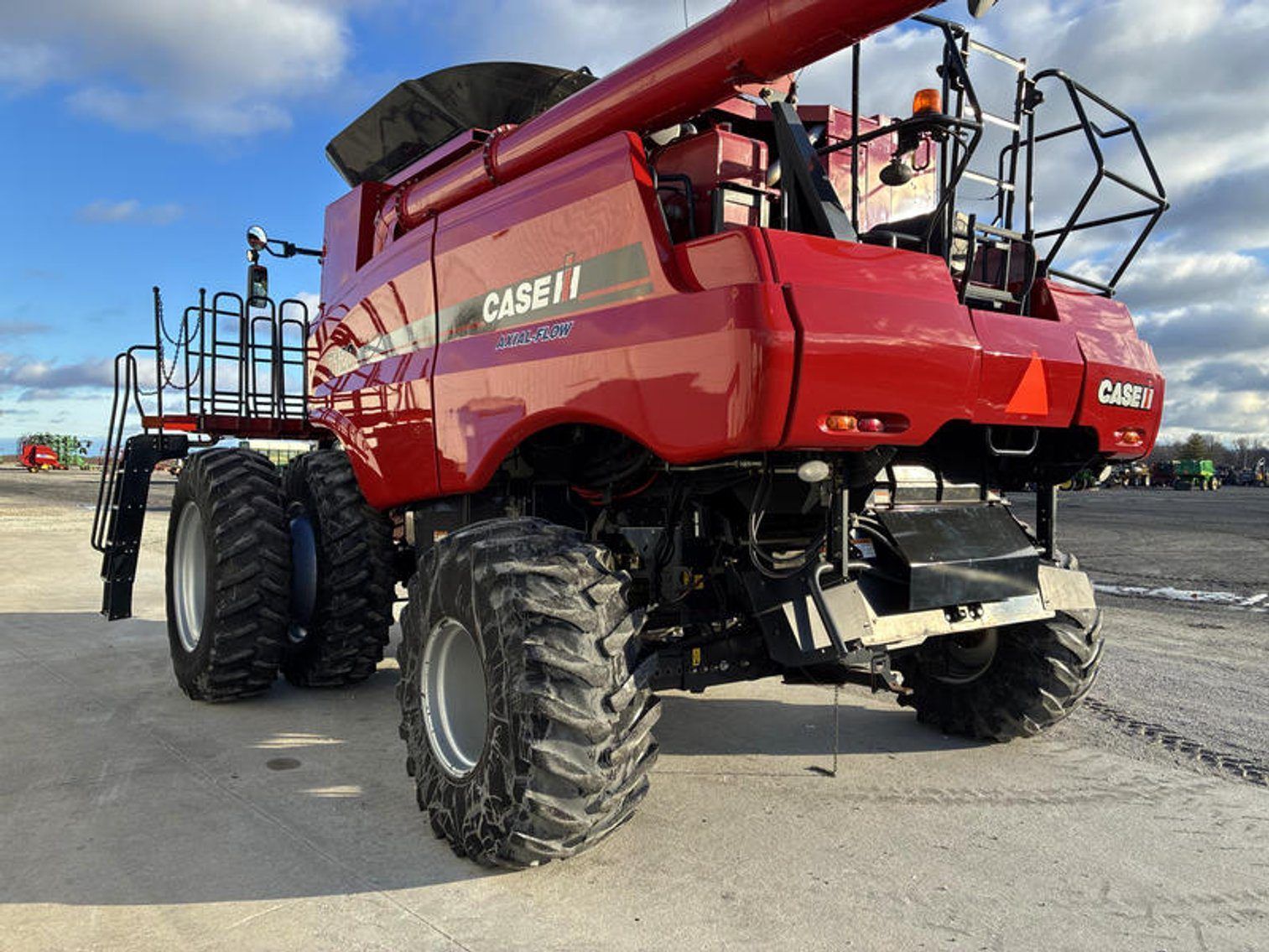 Red Case IH combine harvester parked on a gravel lot under a blue sky.