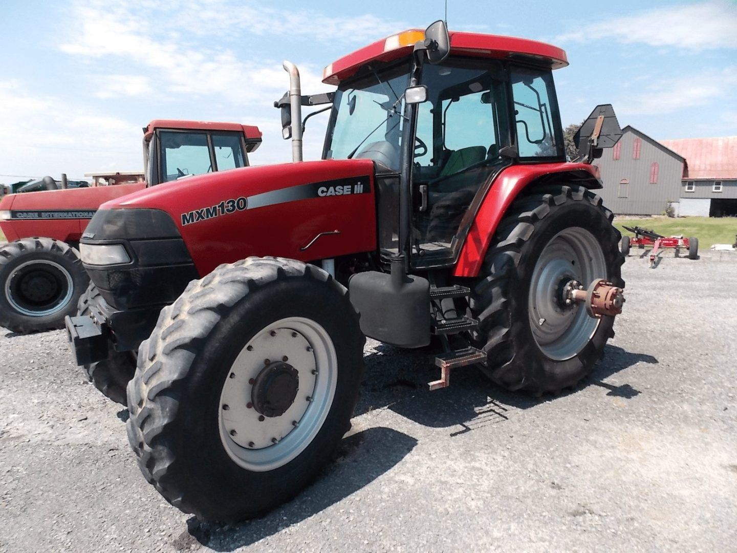 Red Case IH tractor parked on a gravel lot under a blue sky