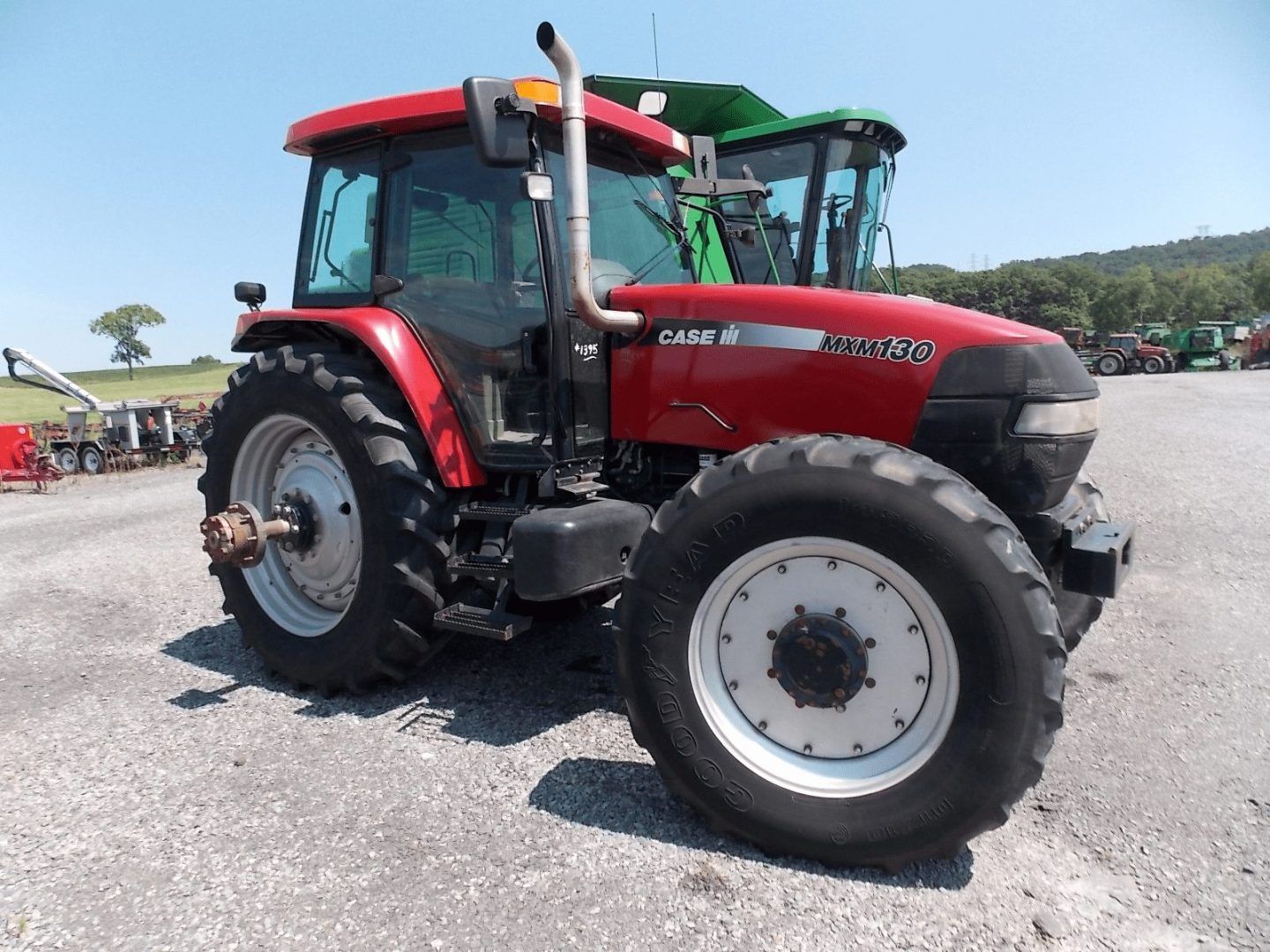 Red Case IH tractor parked on gravel at an outdoor lot with green hills in the background