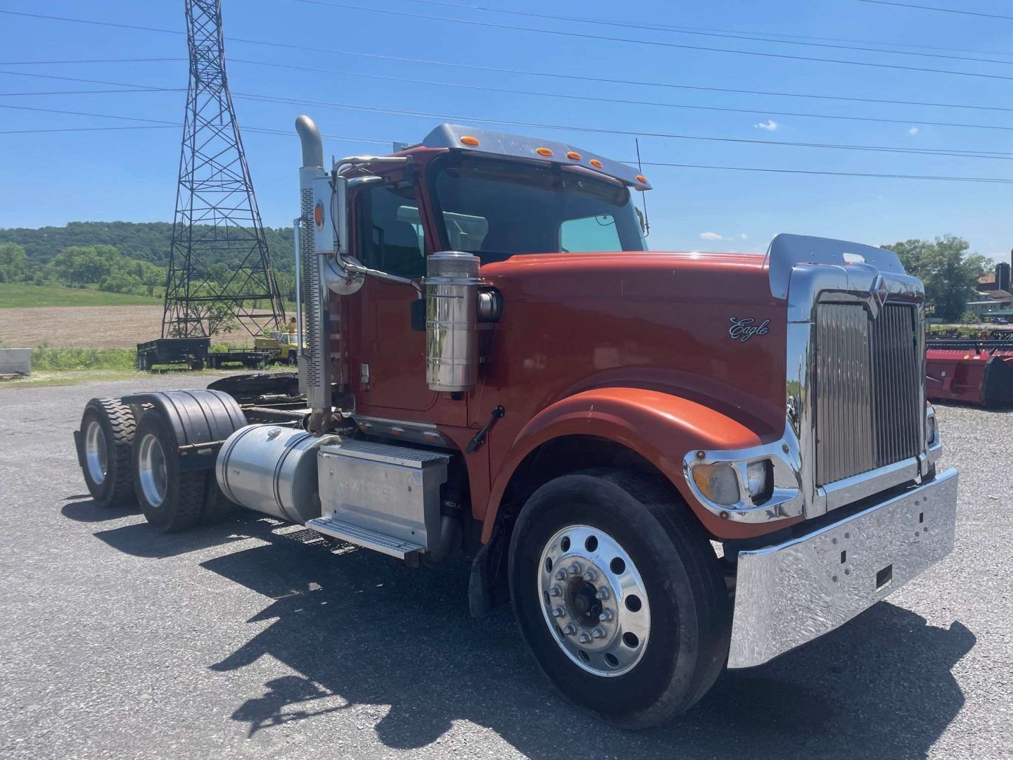 Red semi-truck parked on a gravel lot under a clear sky