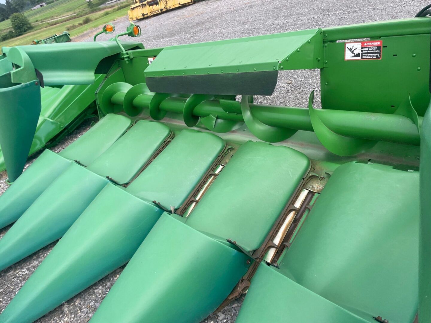 Green agricultural combine header with corn intake cones and metal rollers