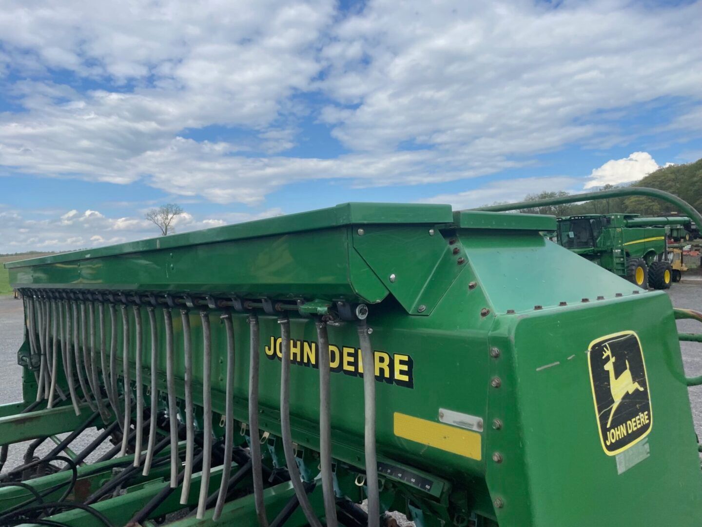 Green John Deere farm equipment under a cloudy sky at an outdoor field display