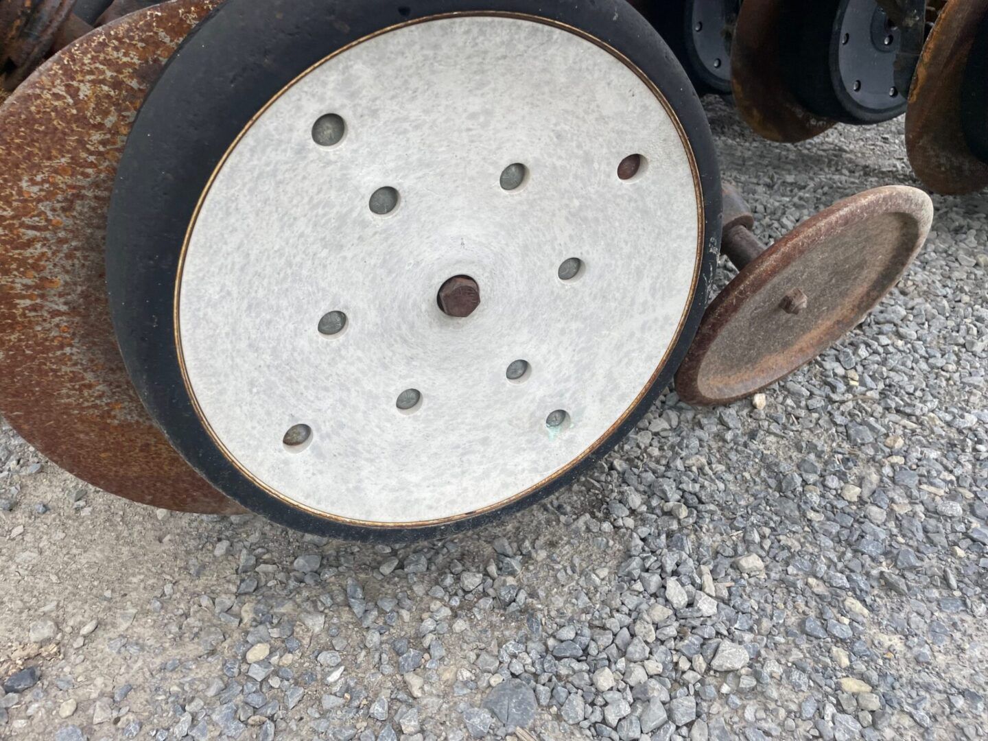 Rusty metal wheels or rollers with white circular centers on gravel.