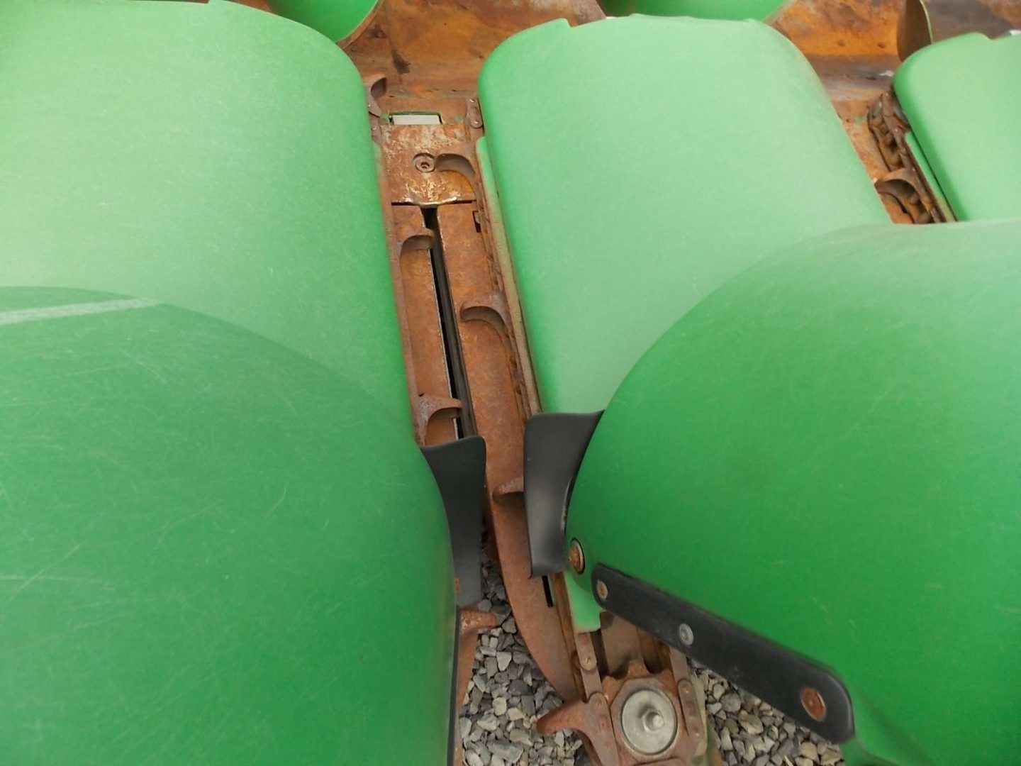 Green plastic seats with a narrow rusty metal gap between them and visible mechanical parts underneath
