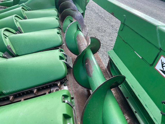 Green conveyor belt with curled black edging carrying wrapped items in an industrial setting