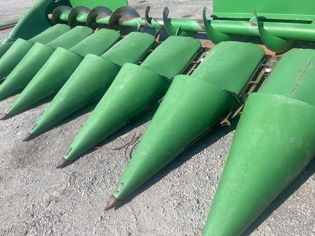 Green conical machine parts lined up on pavement outdoors