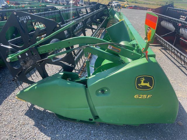 Green John Deere 625F combine header on display at an outdoor farm equipment lot