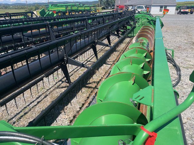 Green agricultural conveyor machine in a farm equipment yard, viewed from above.