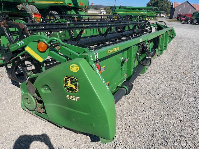 Green John Deere agricultural implement parked on gravel, with black framework and yellow logo.