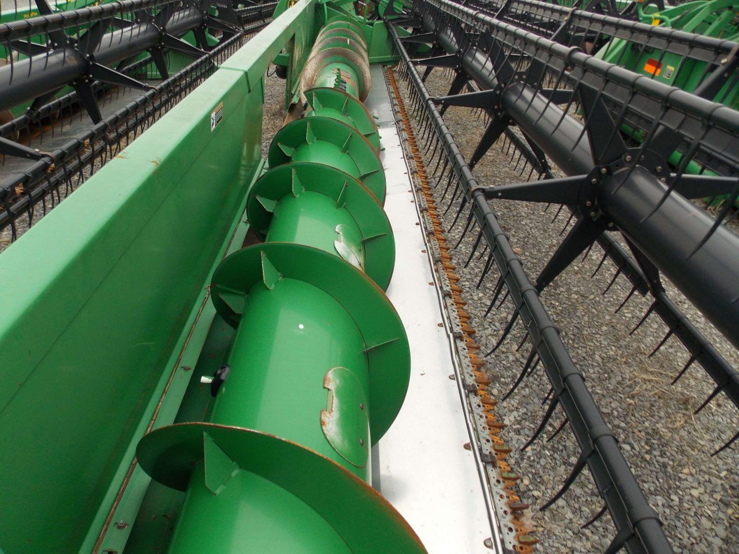 Green industrial auger conveyor with helical blades in a factory setting