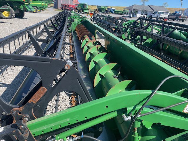 Green agricultural combine header close-up in a farm equipment lot