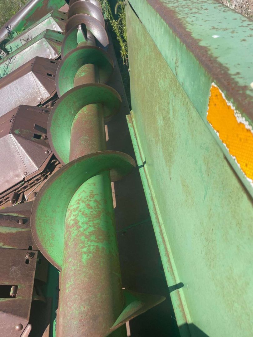 Green auger conveyor inside industrial machinery with worn paint and metal components