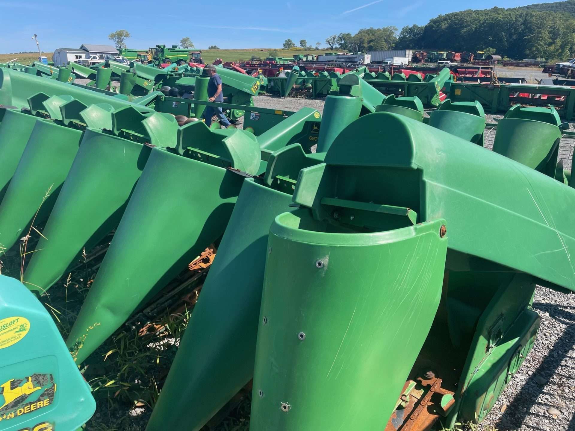 Rows of green metal trash bins stacked outdoors in a sunny yard