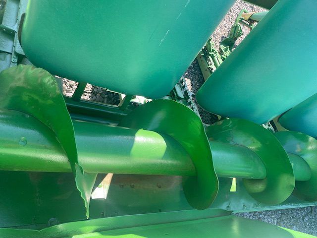Green plastic playground equipment close-up, with curved bars and seats in bright sunlight