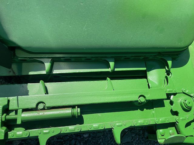 Green machinery with metal rollers and brackets close-up