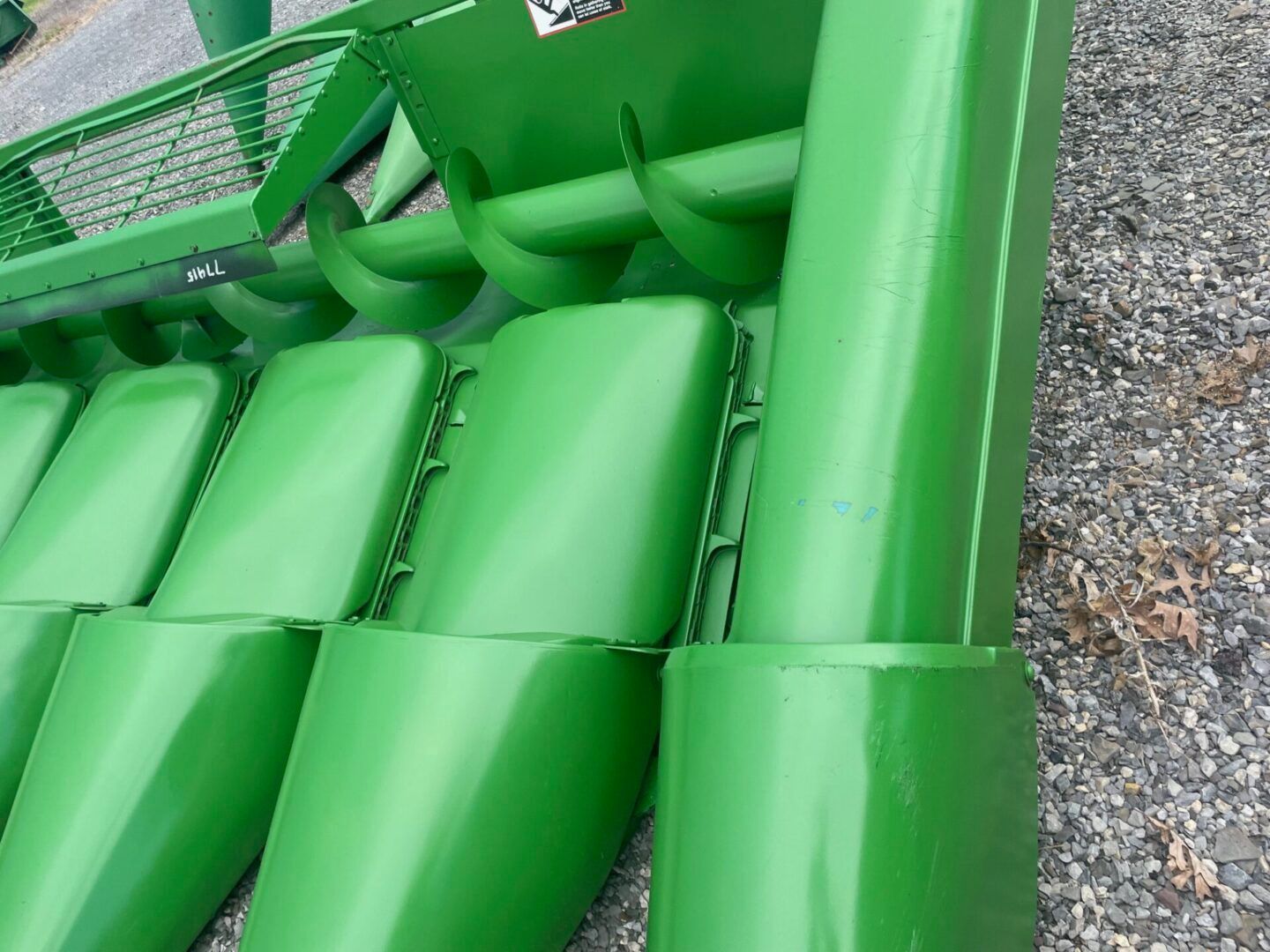 Close-up of bright green inflatable gym mats stacked beside a metal fence outdoors