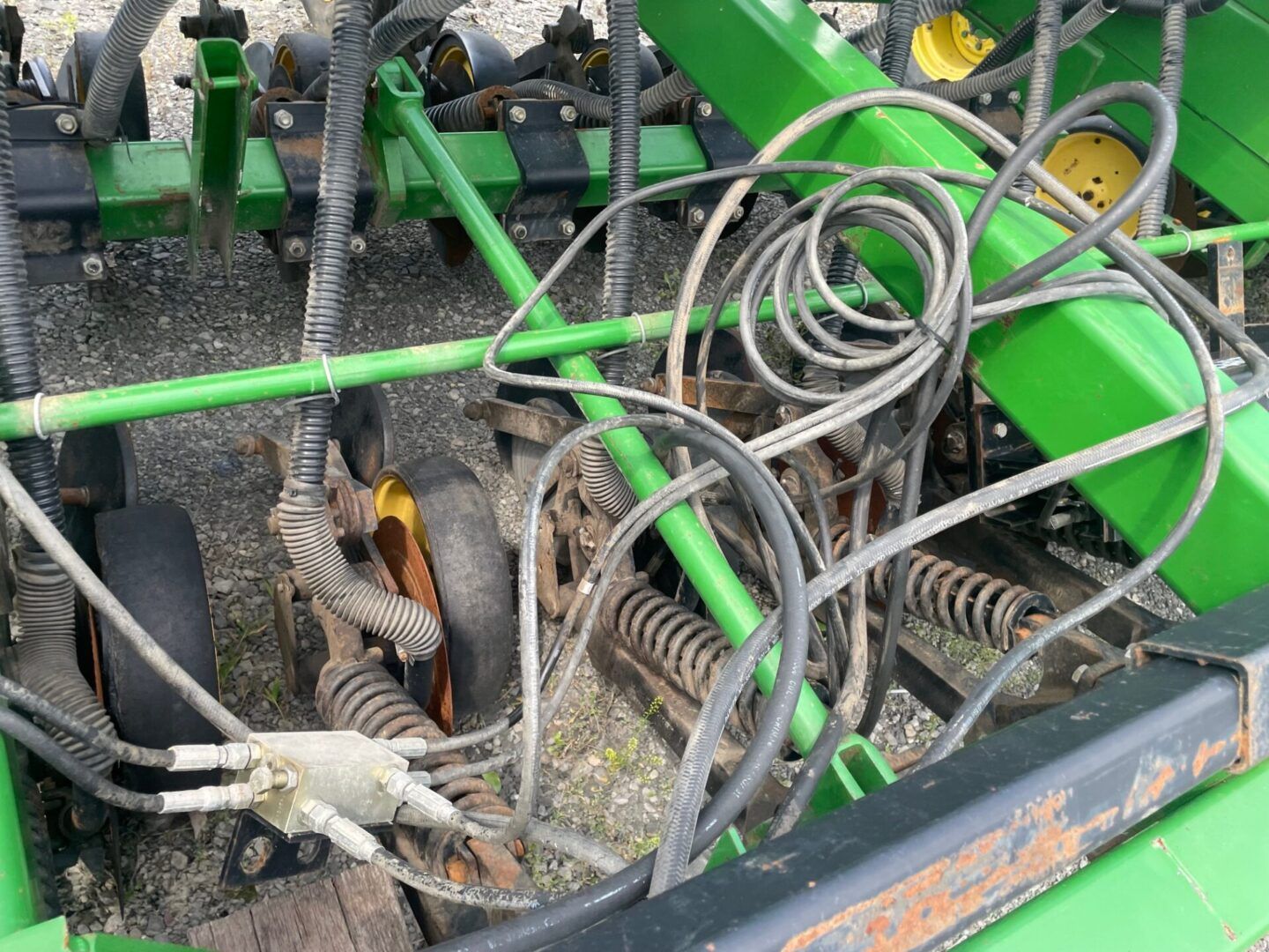 Close-up of tangled green and gray farm machinery with coiled cables and metal springs.